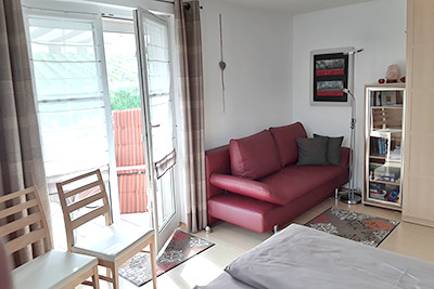 Schlafzimmer mit Doppelbett, Sofaecke und Zugang zum Balkon