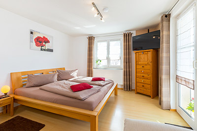 Schlafzimmer mit Doppelbett, Sofaecke und Zugang zum Balkon